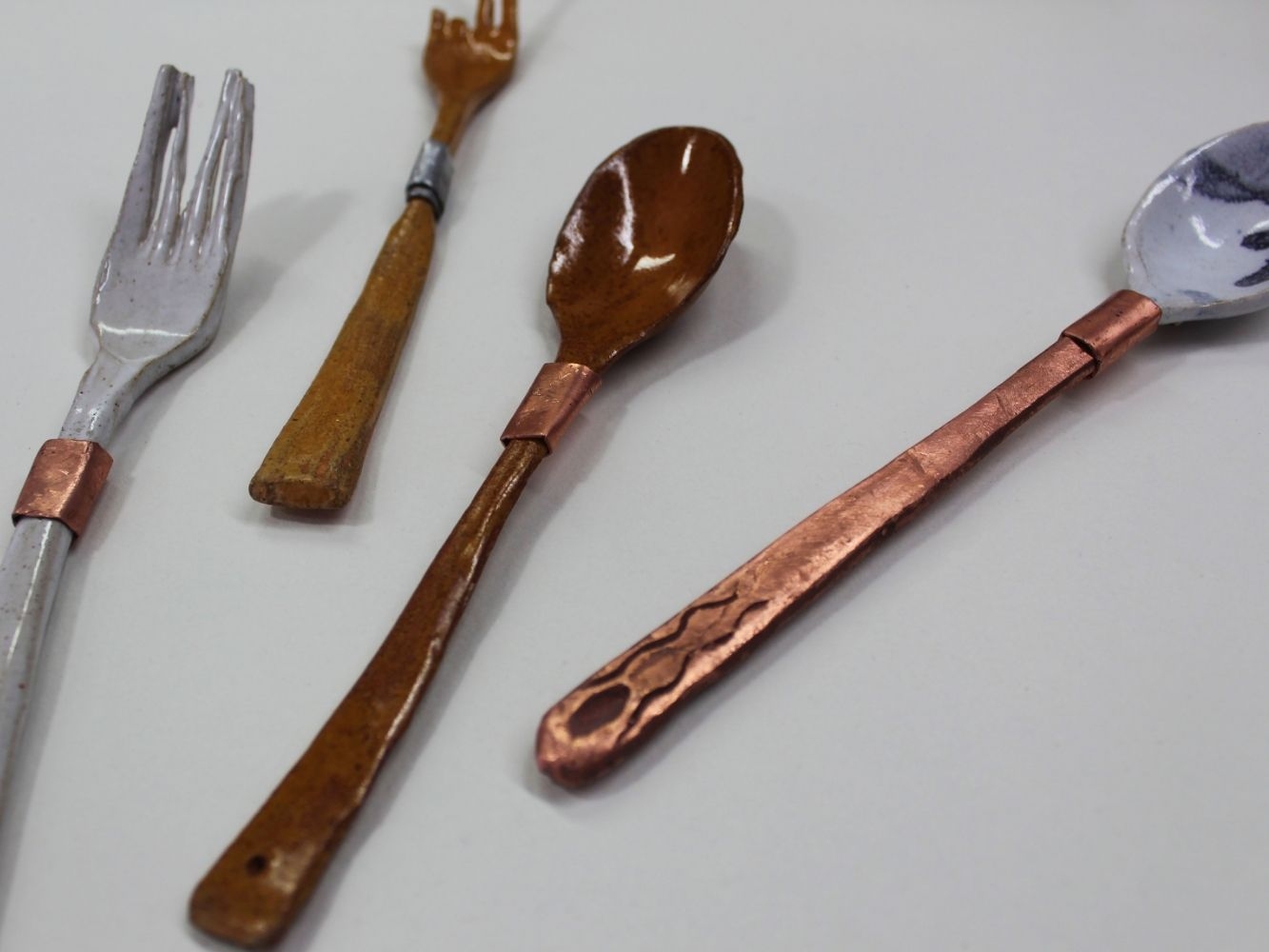 Various silver and copper coloured cutlery scatted on a table