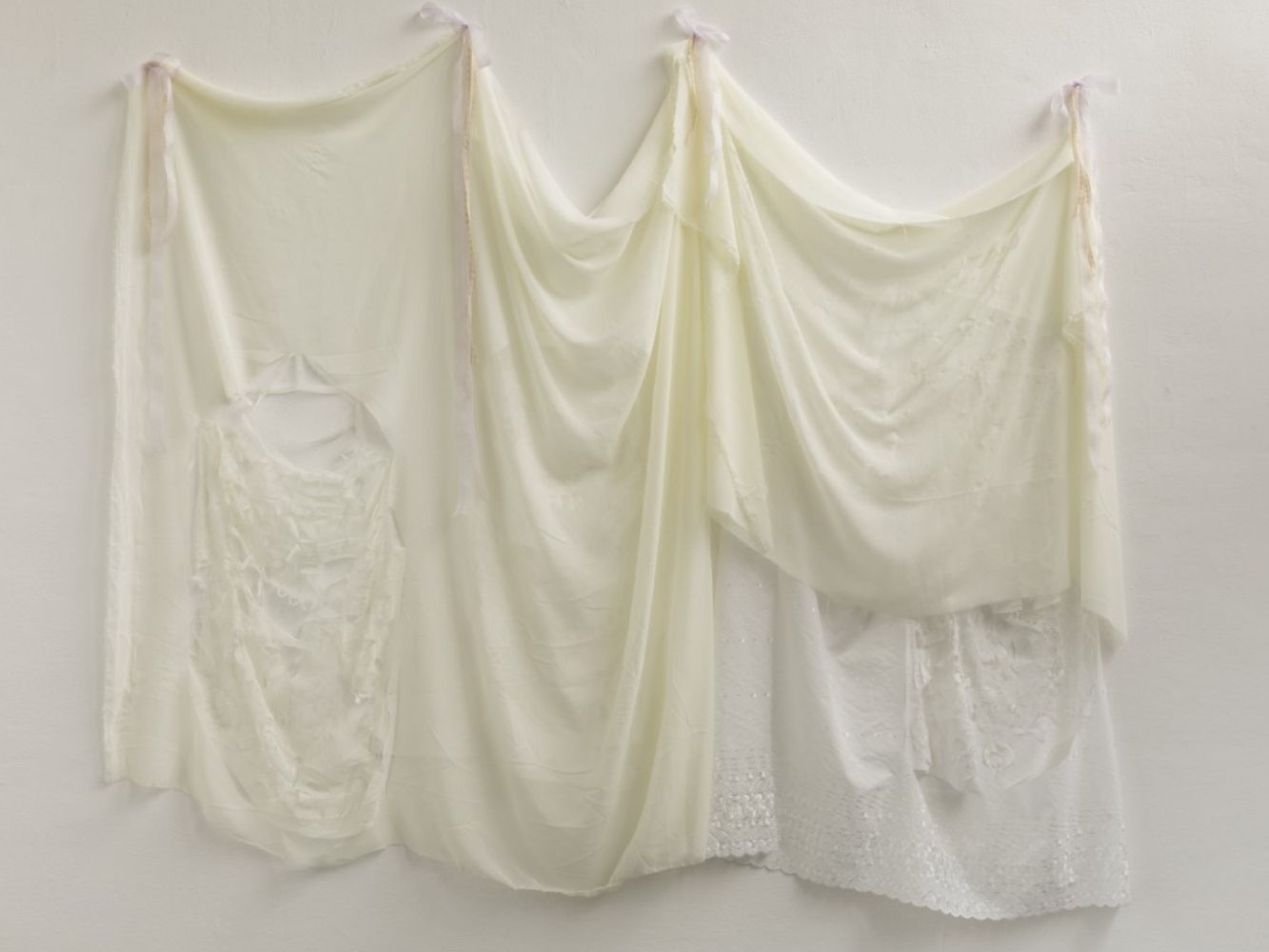 Cream coloured sheet draped on a white wall