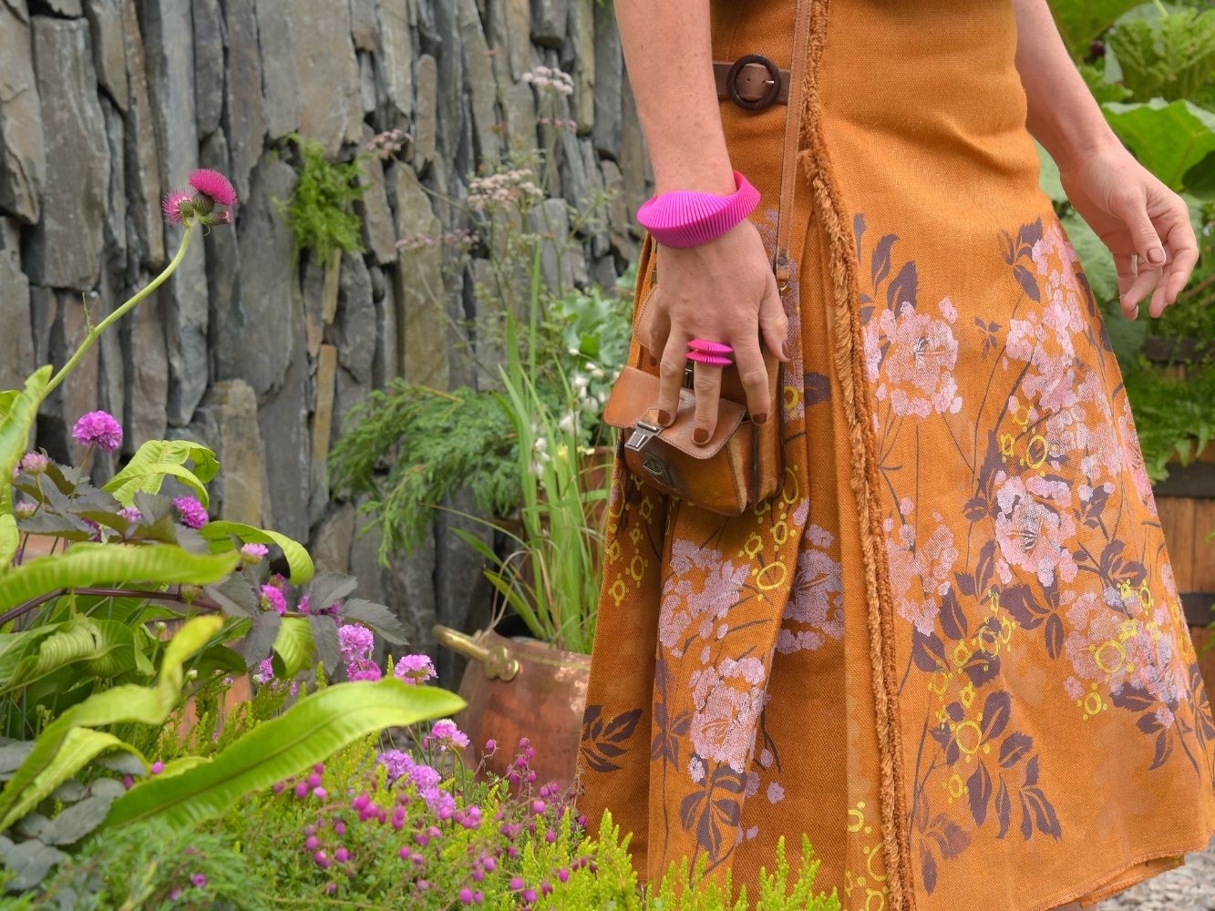 Model wearing orange, flower printed skirt walking through a garden
