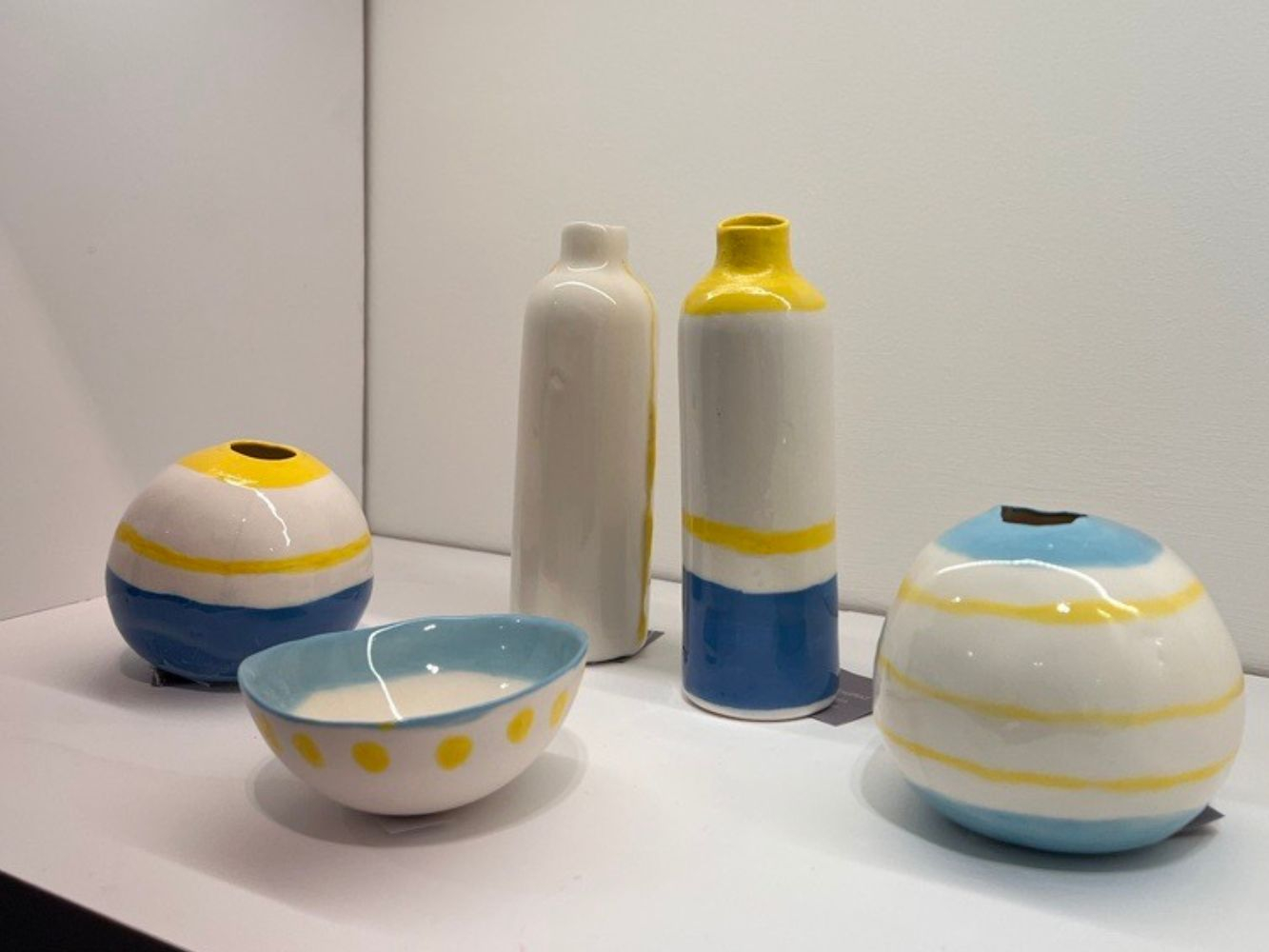 A display of yellow, blue and white coloured bowls and vases