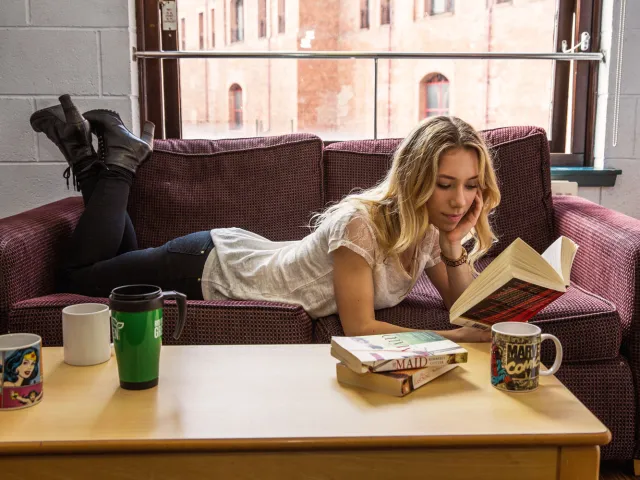 student reading a book on the sofa in student accommodation