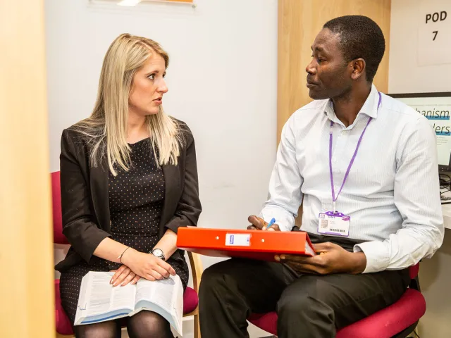 two people chatting holding books and a binder