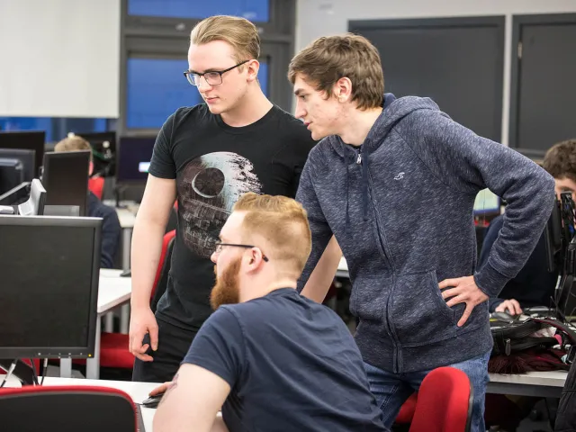 three students looking at a computer monitor together