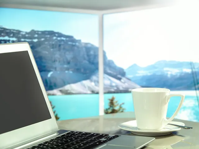 laptop and coffee cup in front of picturesque landscape