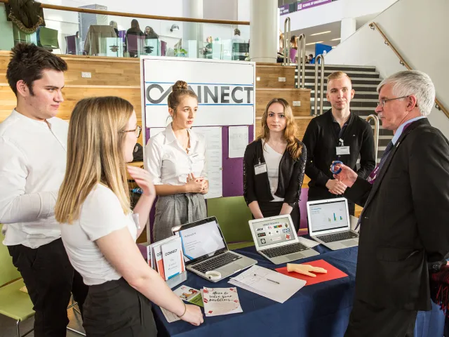 students at an event listening to a man in a suit