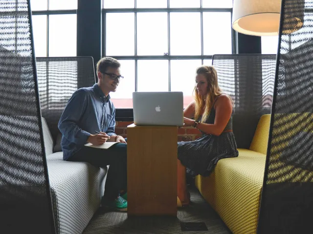 two students looking at a laptop in a study area