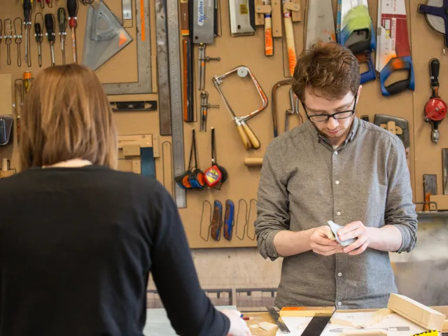 students working in front of a wall of tools