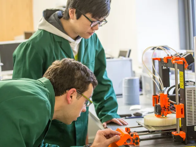 engineering students looking at a 3D printer