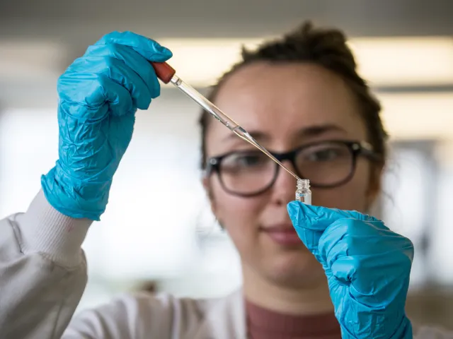 woman using a dropper to put liquid in a test tube