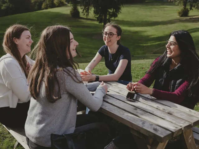 students chatting on a picnic bench