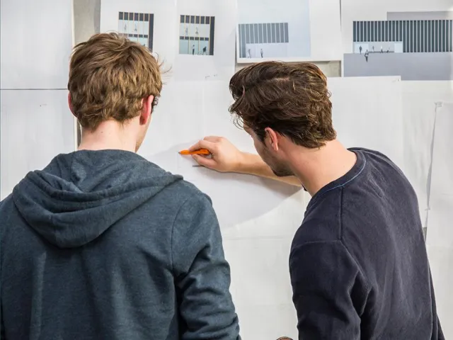 two people looking at technical drawing on a wall