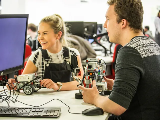 two students smiling holding robotics kits