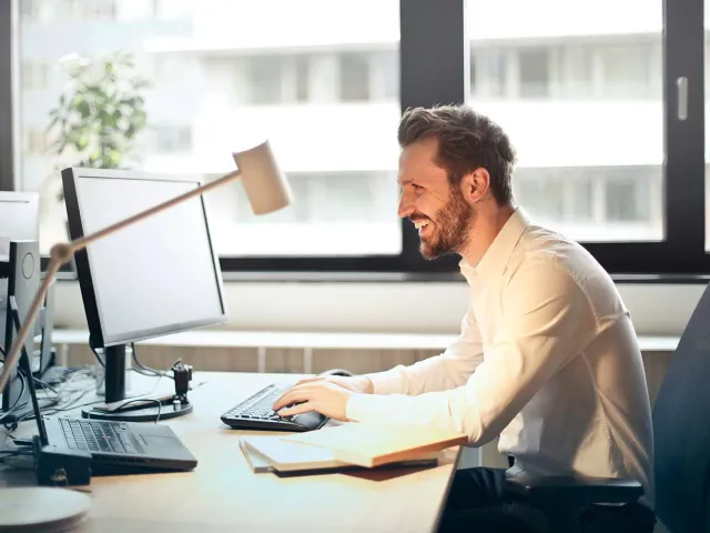 man smiling at computer desk