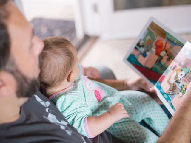 Man holding a baby and reading a book