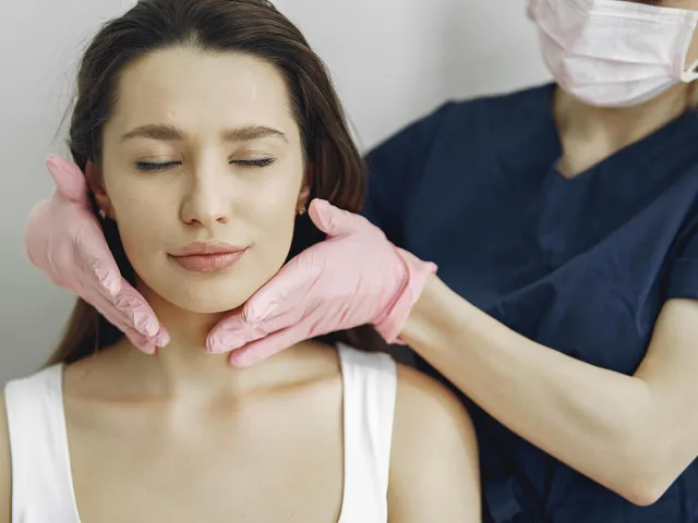 person with medical gloves on touching another persons face