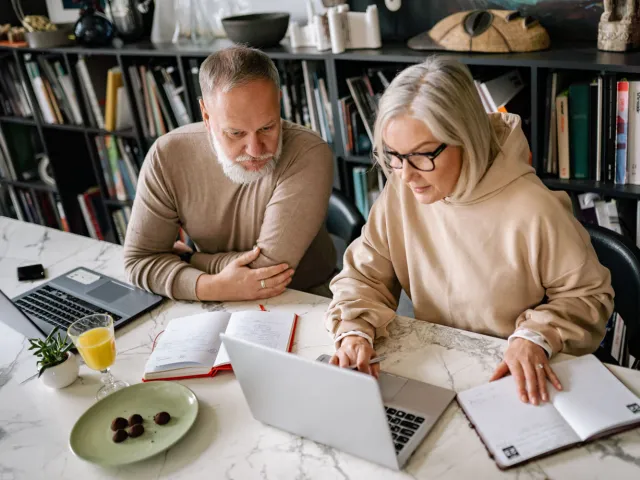 older people working on laptops at a desk