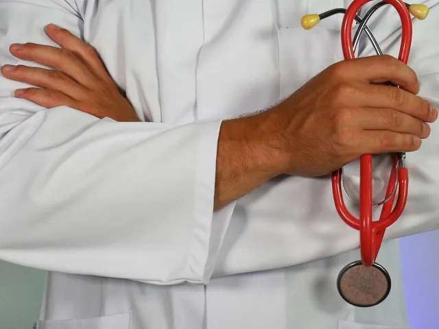 a person in a white coat holding a red stethoscope