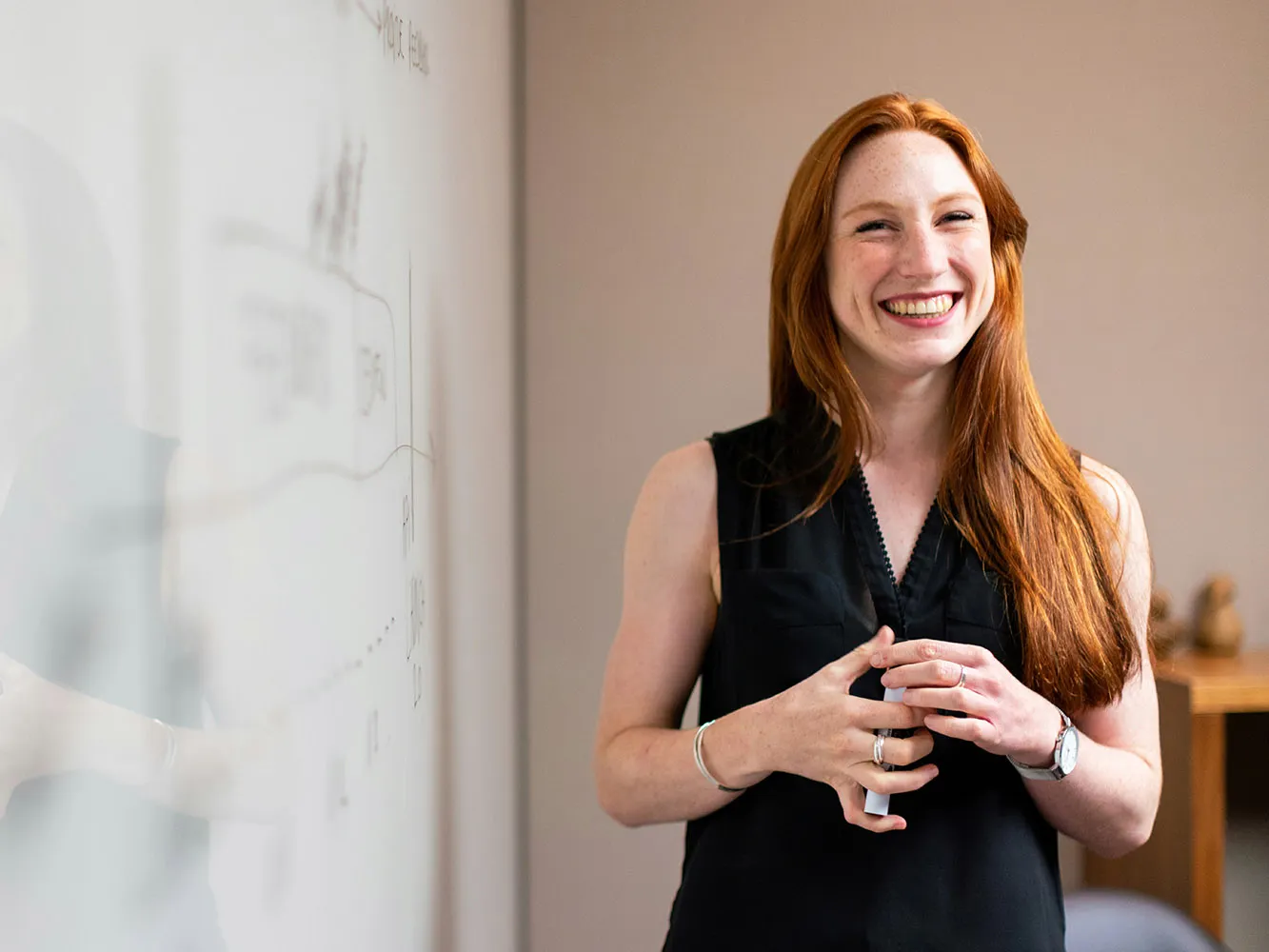 person grinning next to a white board