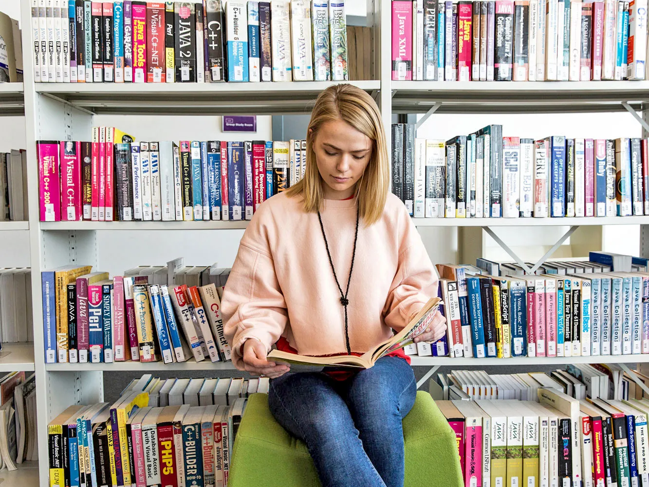 woman reading a book in front of a bookshelf