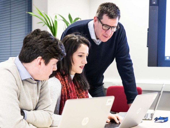 three people working at laptop screens