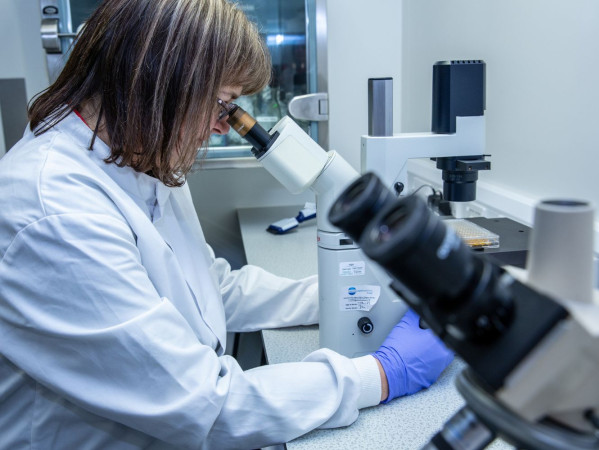 A woman is looking into a microscope