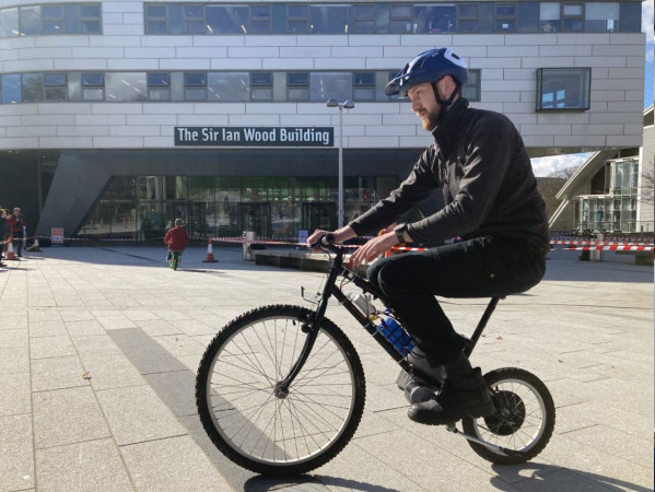Engineering student riding a bike outside RGU's Sir Ian Wood Building