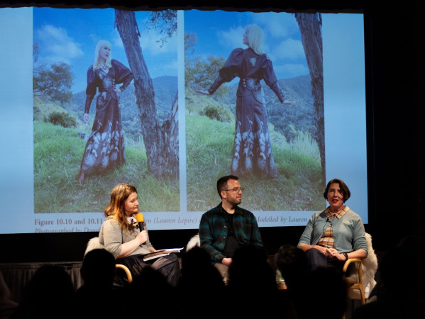 Three people sitting on stage with fashion images behind them