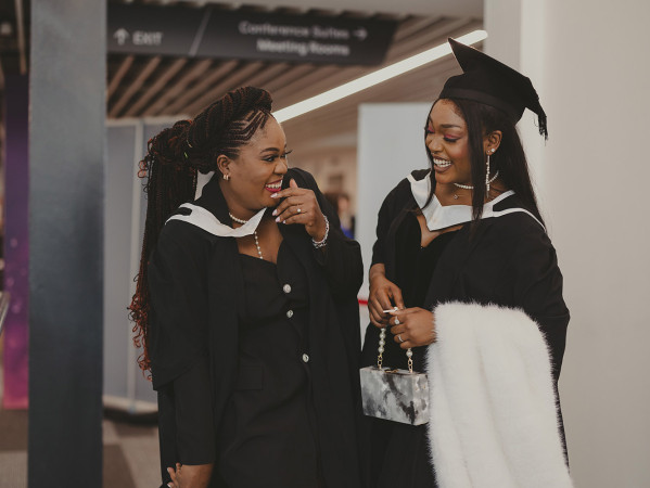 two students at graduation laughing and smiling
