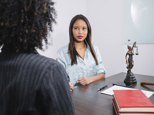 Two ladies talking with Scales of Justice on the table