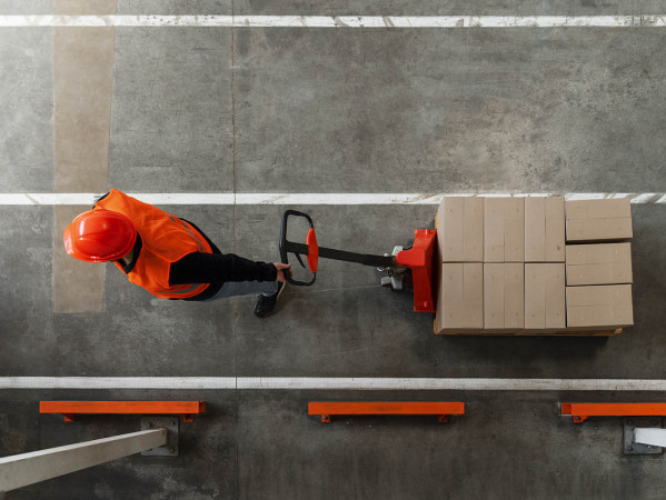 Man pulling a pallet lifter with boxes on - image attribution https://www.freepik.com/free-photo/full-shot-man-working-construction_65550091.htm