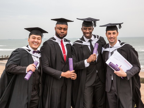 Students in graduation gowns holding their scrolls