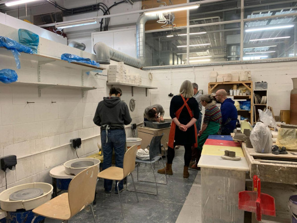 Tutor and student learning how to throw pottery