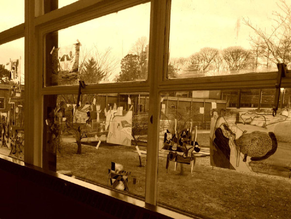 Sepia toned image of a window with artwork stuck to it
