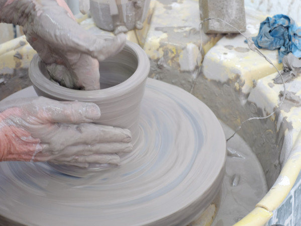 Person throwing a pot on a wheel