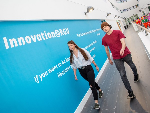 Two people walk through RGU's campus