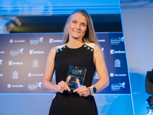 Julie Jones standing in front of a blue background with one of her two awards.
