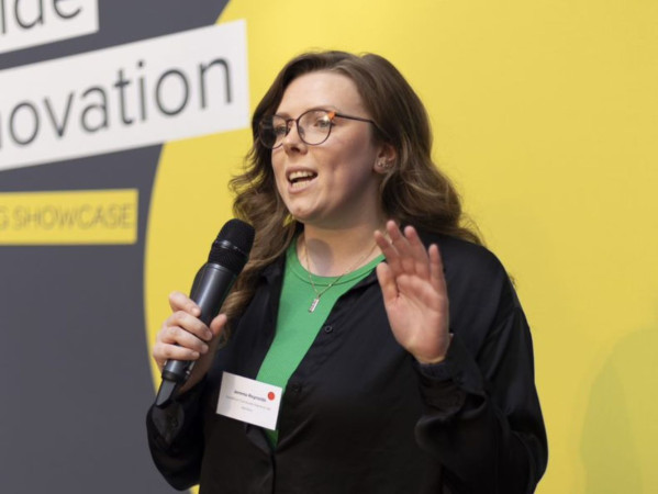 Jemma Reynolds speaking into a microphone Jemma Reynolds speaking into a microphone
