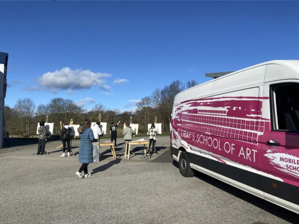 The pink Mobile Art School van with people painting in the background