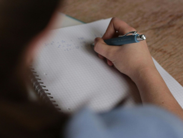 A person writing on a notepad, taken from over the shoulder A person writing on a notepad, taken from over the shoulder