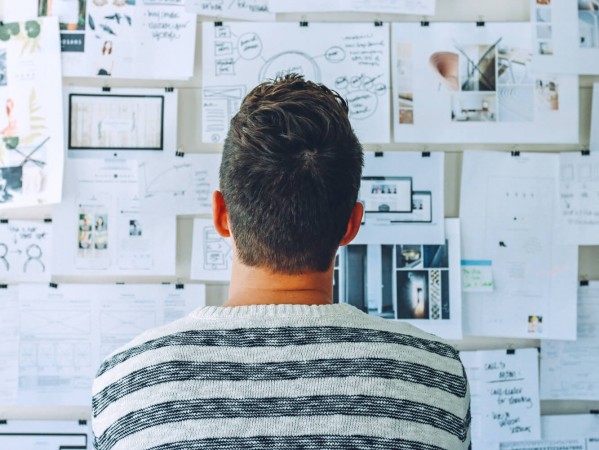 person looking up at a whiteboard with plans and notes on