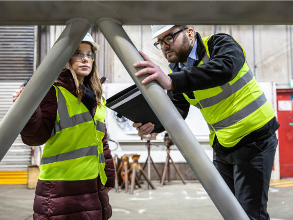 Two people in hi-vis jackets looking at engineering metalwork
