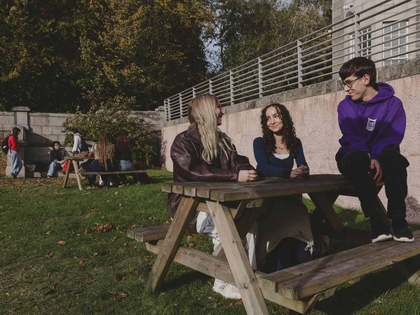 3 students sitting at a bench on RGU's campus
