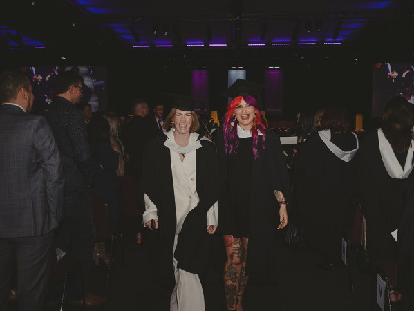 2 graduates leaving the ceremony