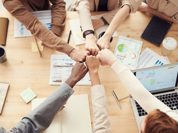 mixed race people fist bumping at a work table