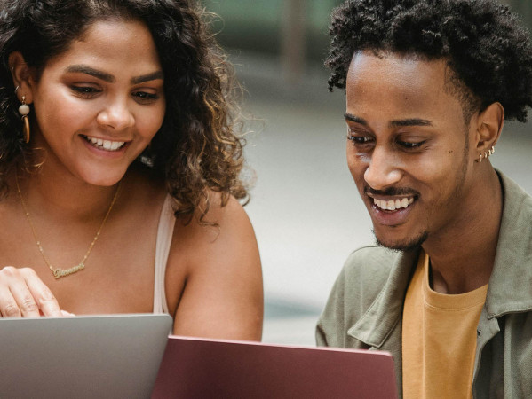 two students look at laptop screens outside