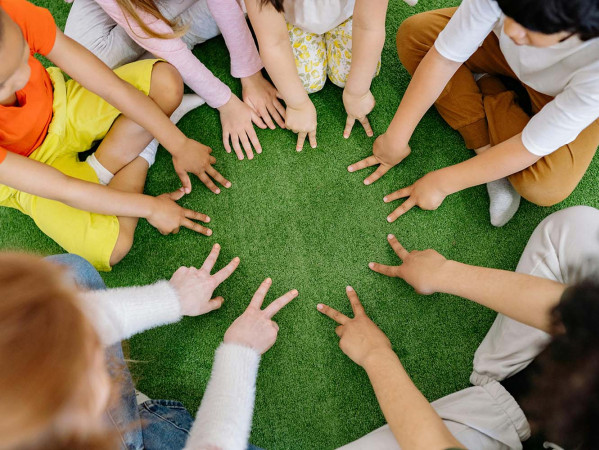 Children sitting in a circle with their hands together in the middle