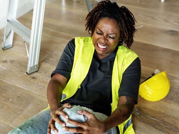 Person in high-vis holding their knee in pain Person in high-vis holding their knee in pain