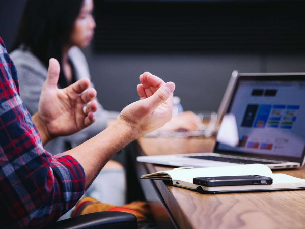 Man waving hands in front of a video call on a laptop