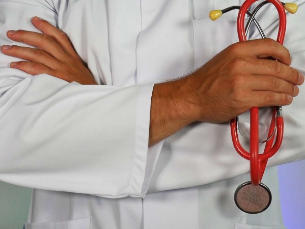 a person in a white coat holding a red stethoscope