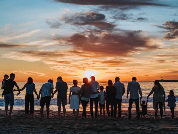 people standing arm in arm with a beach sunset